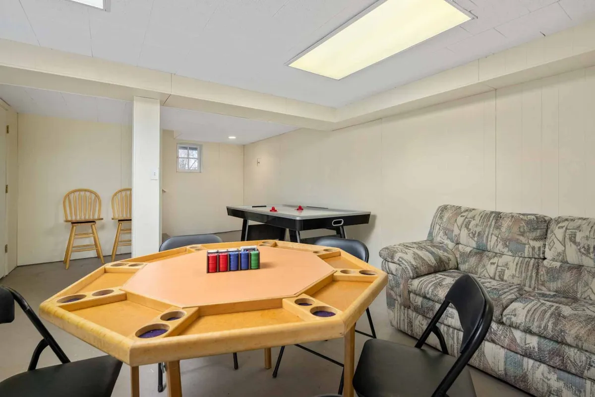 This image showcases a lively game room complete with a game table, sofa, and an air hockey table. The playful setup is ideal for both children and adults, suggesting an environment that encourages socializing, fun, and friendly competition. The relaxed vibe is further accentuated by comfortable seating, making it a hub for various activities.
