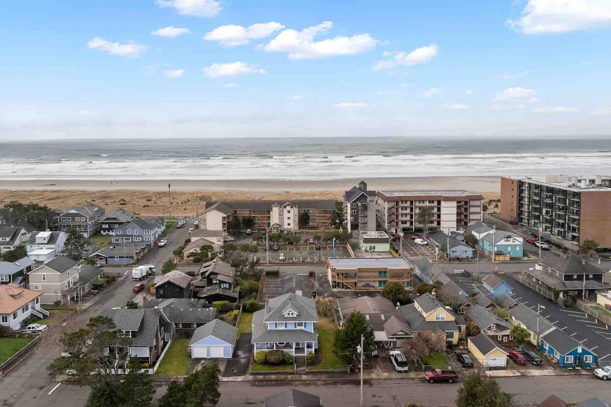 A sweeping view of the ocean, sandy beach, and nearby buildings, with streets leading from the water inland. The scene captures the easy flow between beach, shops, and the community, inviting visitors to explore both natural and urban attractions within walking distance.