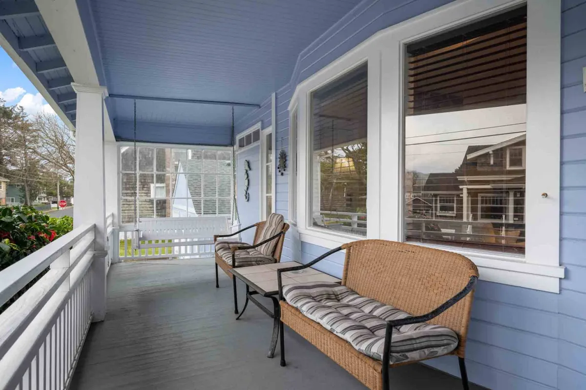 This image shows a relaxing porch swing and woven chairs beneath a charming blue ceiling. The space invites guests to enjoy quiet moments, whether it's sipping tea on a rainy day or reading a book while listening to the rain.
