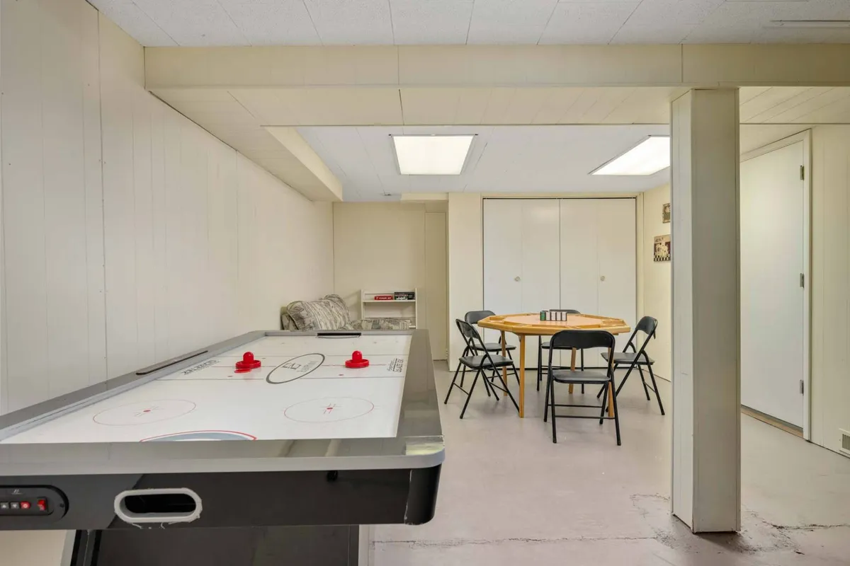 A playful, multi-use space featuring an air hockey table, a dining table with chairs, and a relaxed atmosphere designed for games and family gatherings. The environment encourages fun, connection, and shared activities.